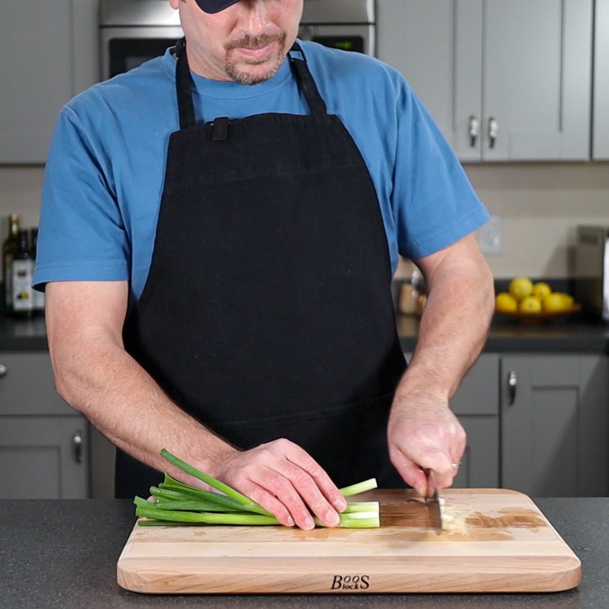 Cutting the ends of a green onion off on a cutting board.
