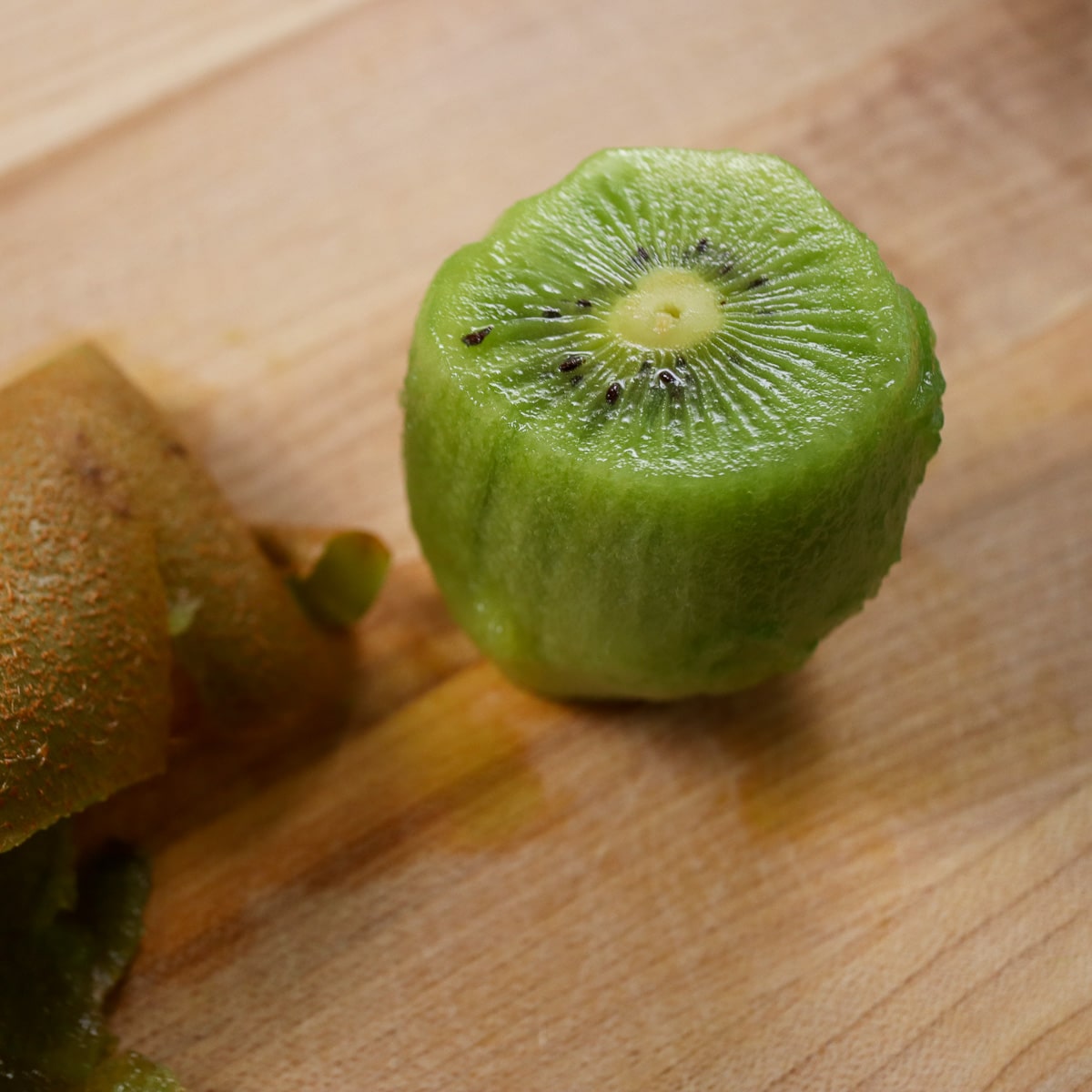 a kiwi fruit peeled on a cutting board
