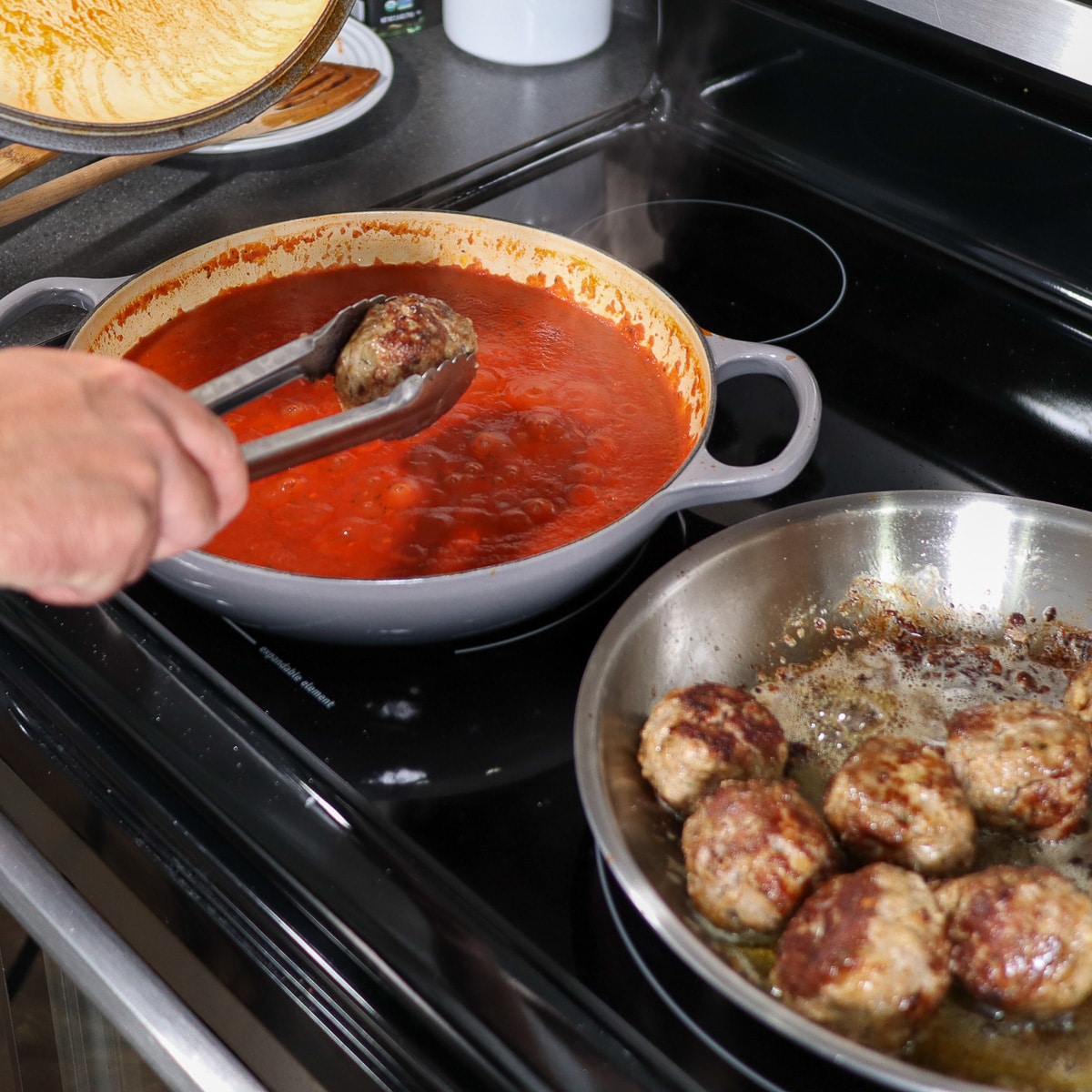 adding meatballs to the pot with the sauce
