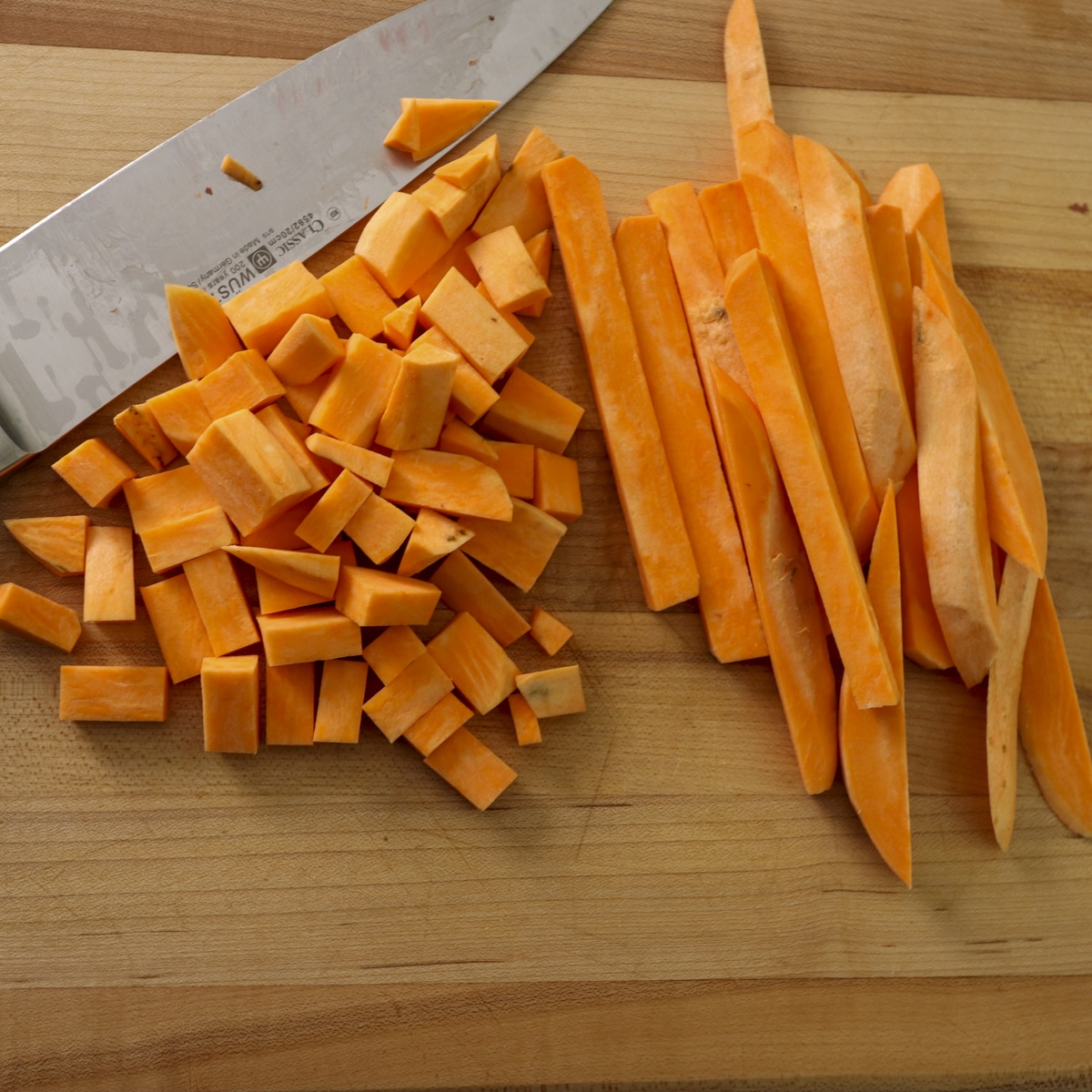 Freshly cut sweet potatoes on cutting board with a chef knife.