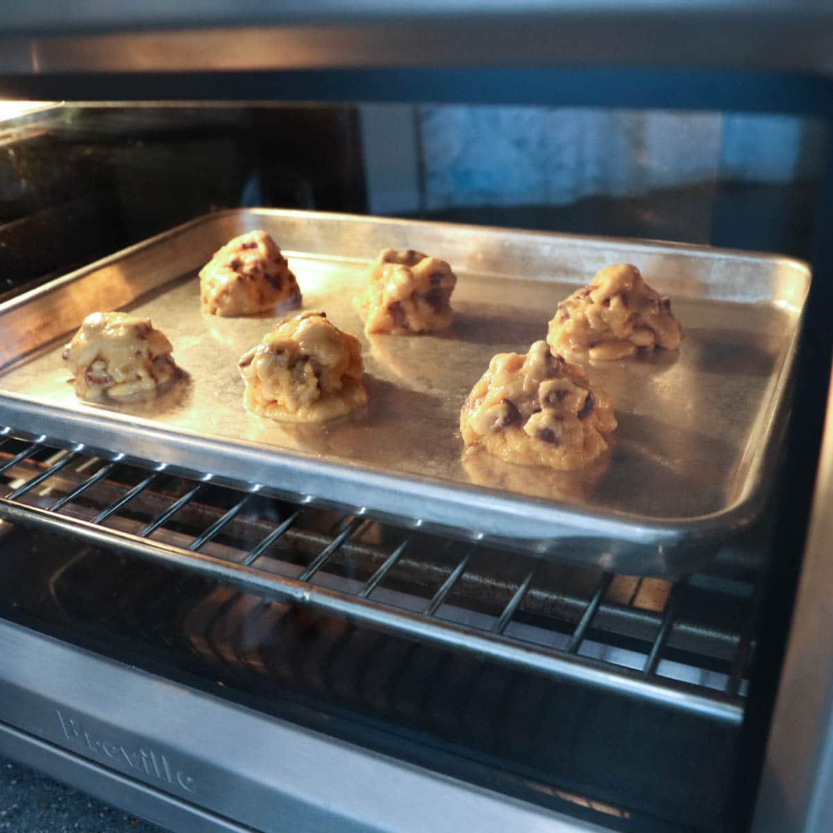 Cookie sheet with 6 cookies starting to bake in the oven.