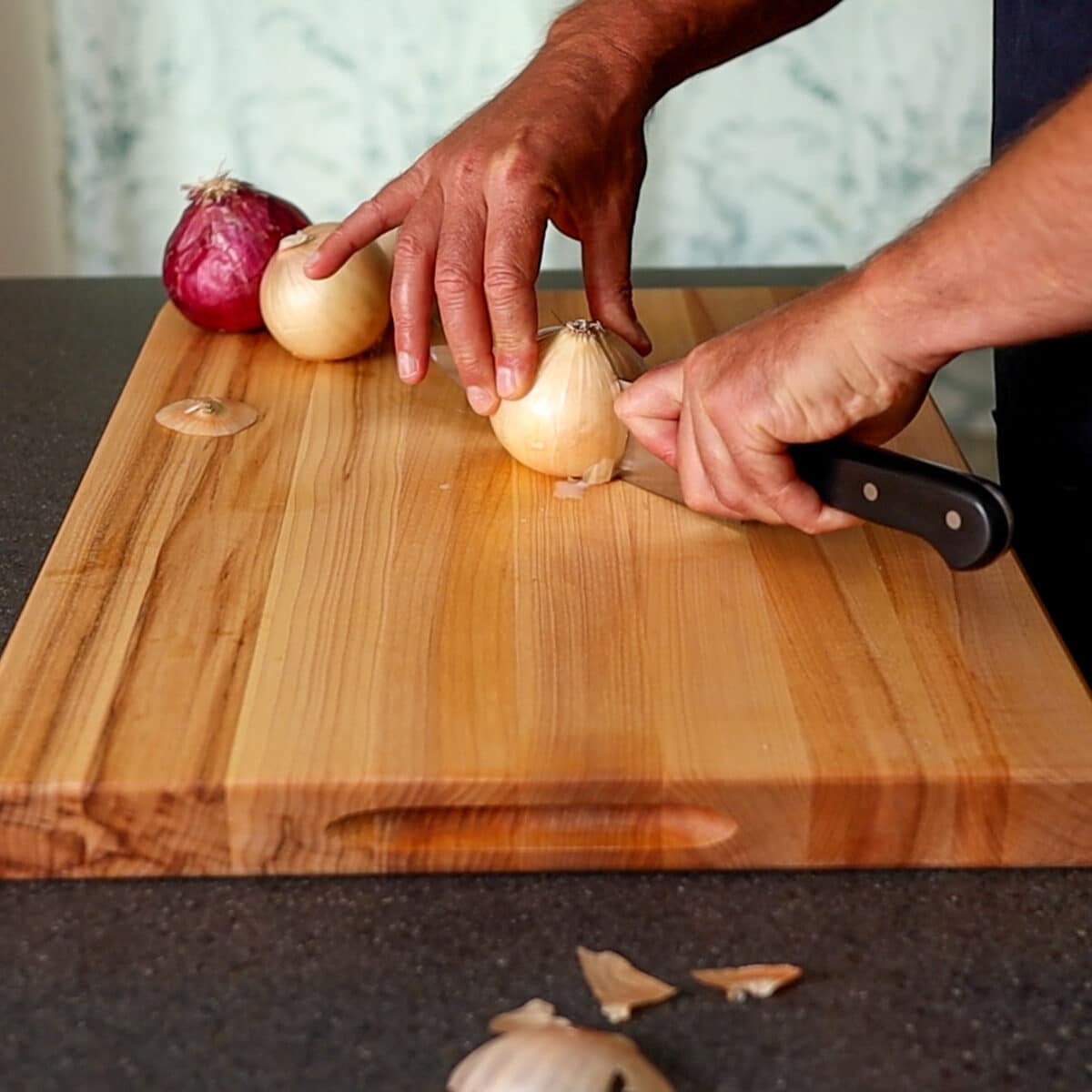 Cutting an onion in half on a cutting board.