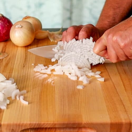 Chopping a white onion on a wooden cutting board