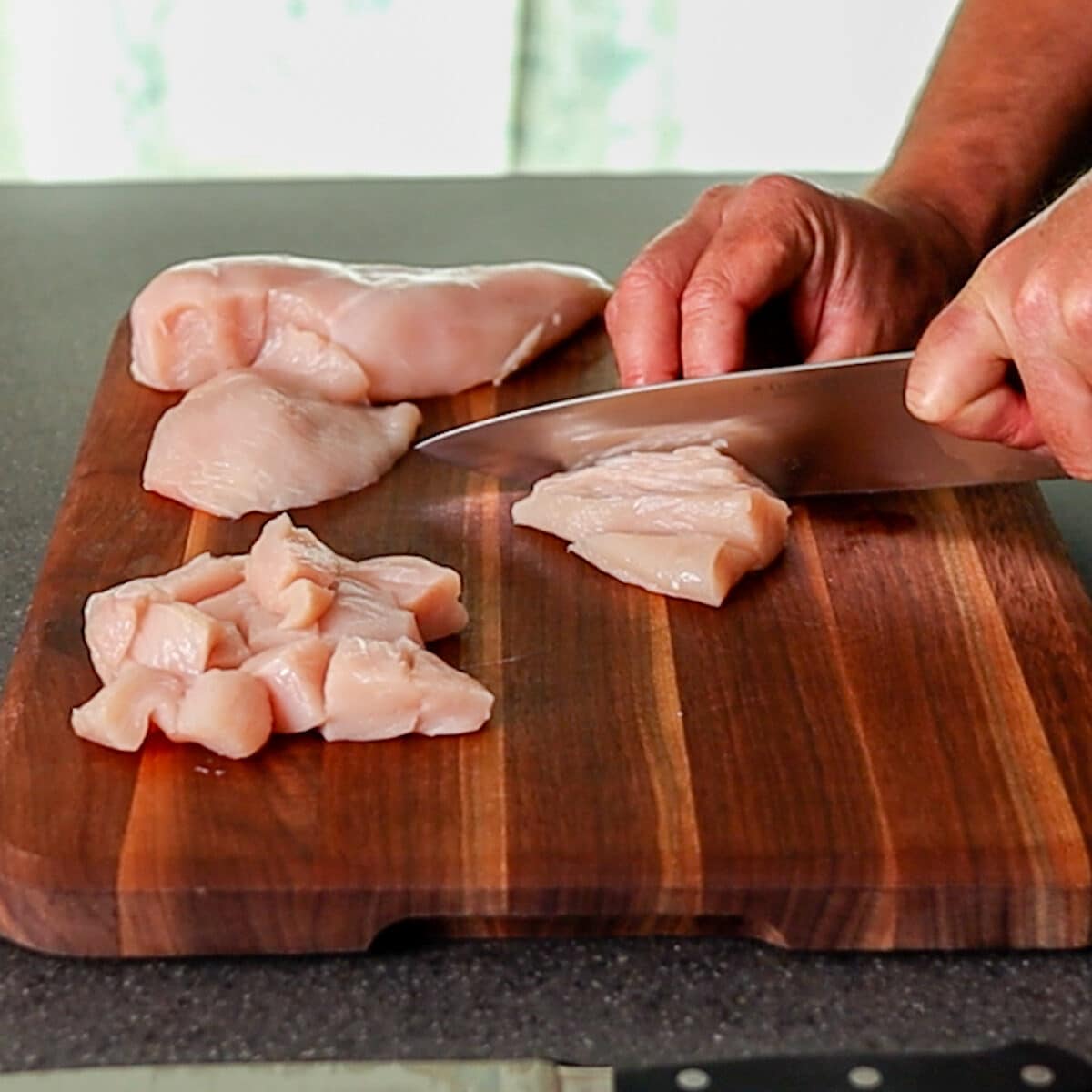 chicken breast being cut up on a cutting board