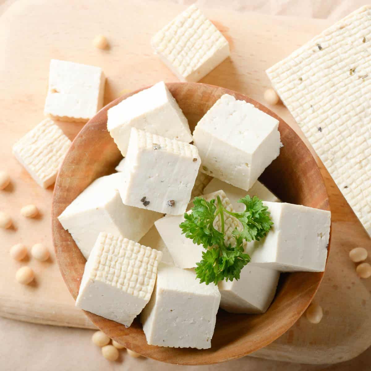 Wooden bowl with cubed tofu and a sprig of parsley