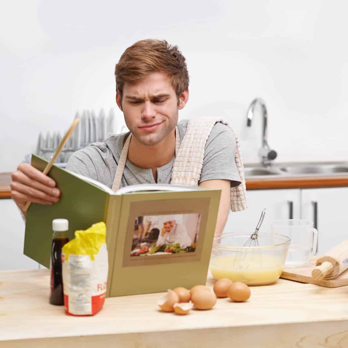 Confused man trying to read a recipe book.