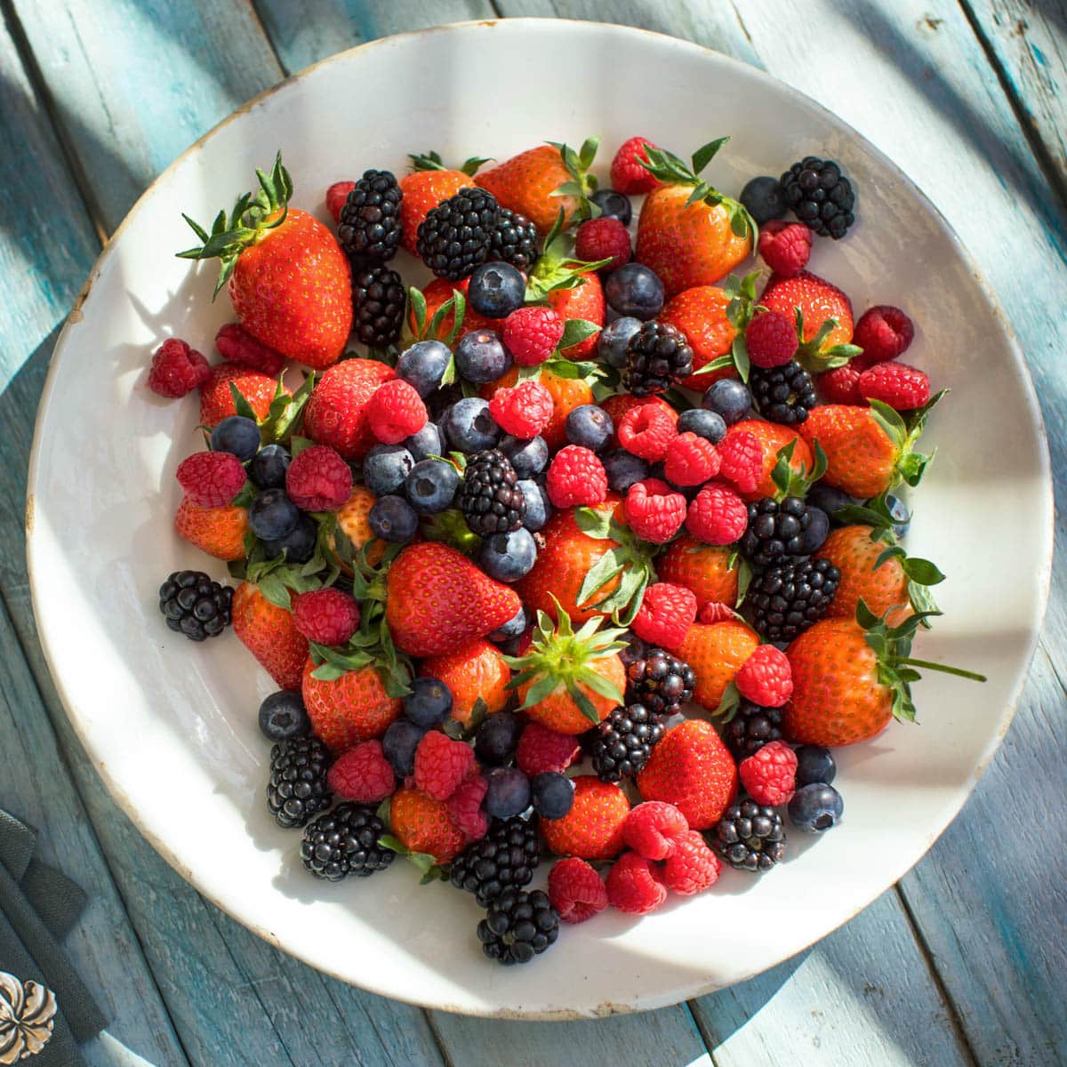 An overview of a plate full of mixed berries on a picnic table