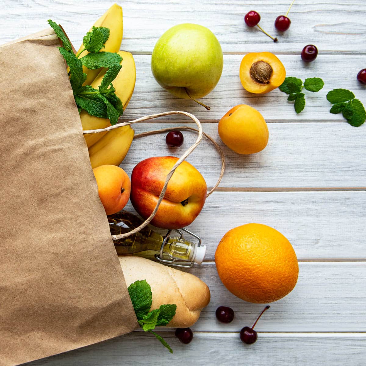 Grocery bag with fresh fruits and vegetables pouring out onto a table.