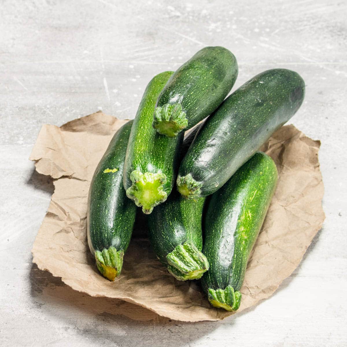 Six fresh zucchini on a paper bag on the counter