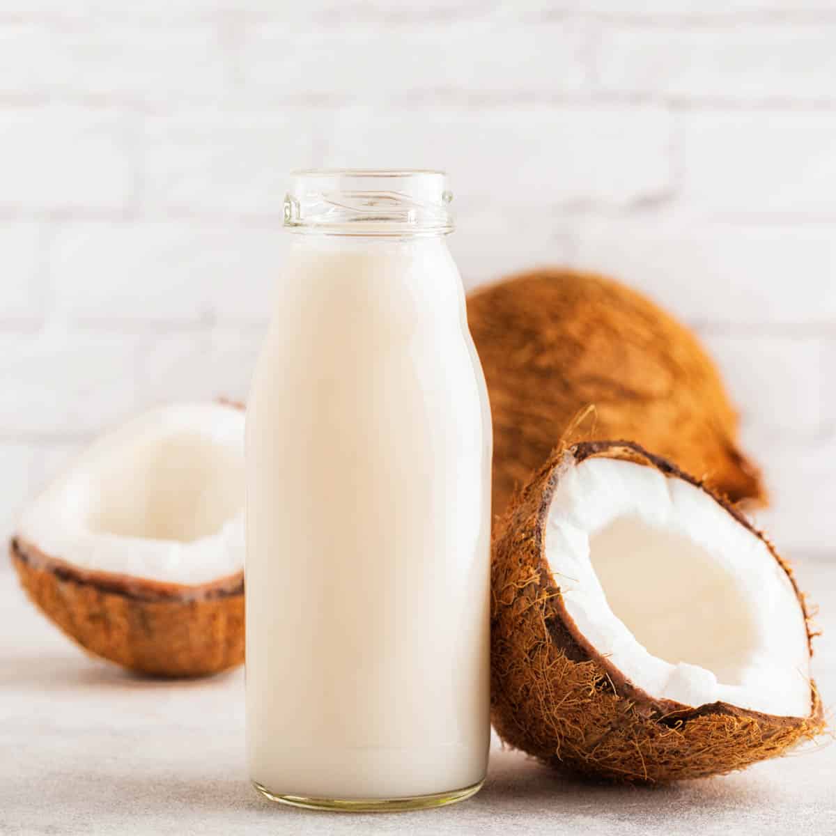 Bottle of coconut milk with fresh coconut on the counter.