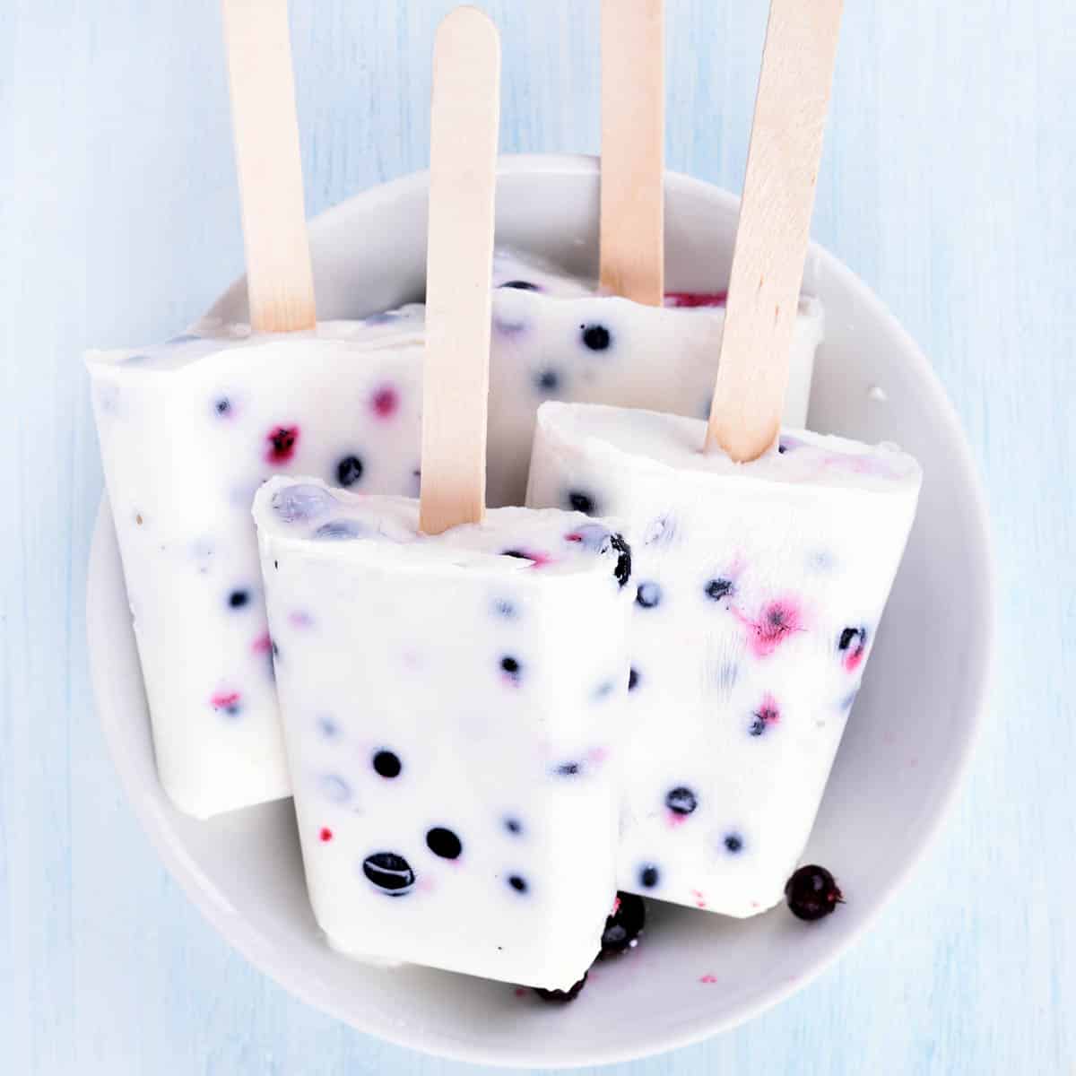 Frozen yogurt popsicles with blueberries in a bowl.