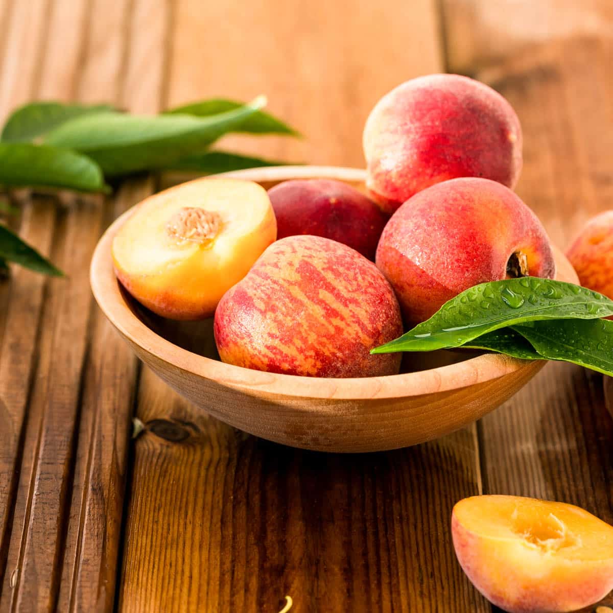 Freshly picked peaches in a wooden bowl.