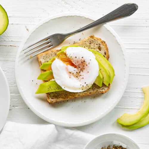 A top view of toast with avocado slices and a poached egg on top.